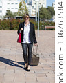 Businesswoman walking with suitcase in city 136763584