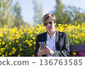 Businesswoman using smartphone in flower park 136763585