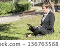 Businesswoman working on laptop in park 136763588