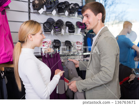 Man shopping for hiking pants with female assistant Man shopping for hiking pants with female assistant 136763671
