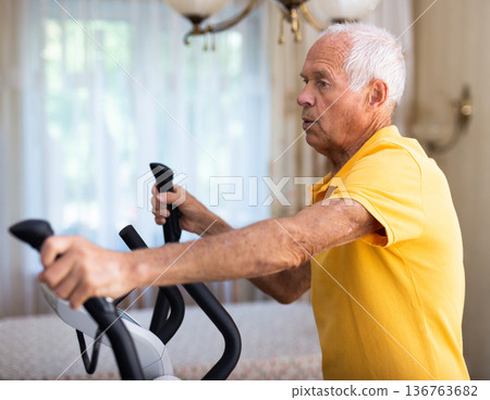 Male is working out on elliptical machine for elder healthy concept Male is working out on elliptical machine for elder healthy concept 136763682