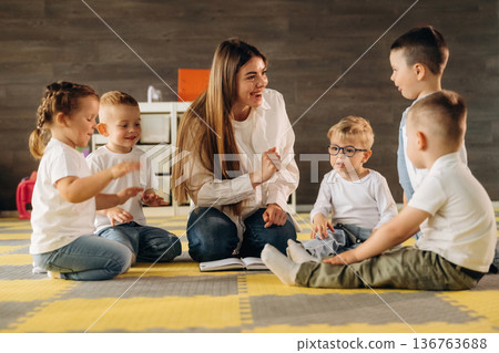 Gathered on the floor, learning. Children in kindergarten with their teacher Gathered on the floor, learning. Children in kindergarten with their teacher 136763688