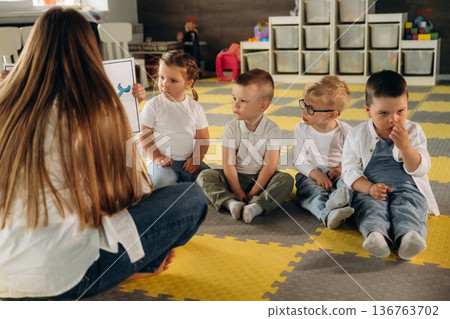 View behind the woman that is sitting and teaching. Children in kindergarten with their teacher 136763702