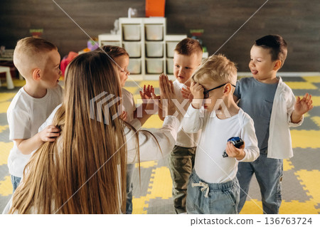 Lesson is over, high five. Children in kindergarten with their teacher 136763724