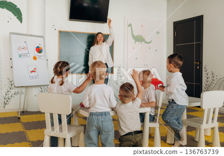 Socialization and education. Children in kindergarten with their teacher Socialization and education. Children in kindergarten with their teacher 136763739