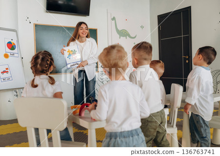 Socialization and education. Children in kindergarten with their teacher Socialization and education. Children in kindergarten with their teacher 136763741