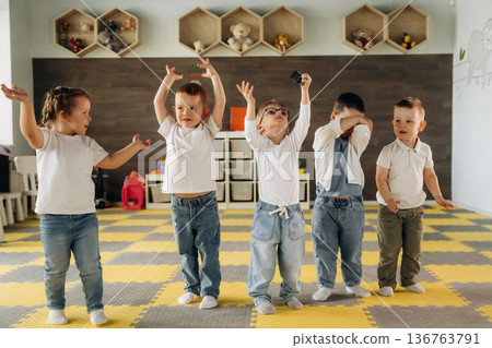Hands up, standing having fun. Group of children are in the kindergarten Hands up, standing having fun. Group of children are in the kindergarten 136763791