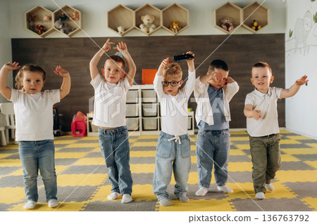 Hands up, standing having fun. Group of children are in the kindergarten Hands up, standing having fun. Group of children are in the kindergarten 136763792