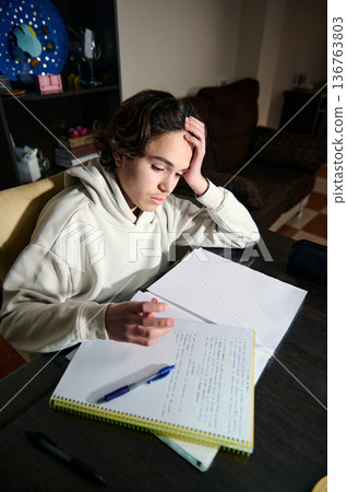 Teenage Boy Doing Homework In The Evening At A Cozy Home Interior 136763803