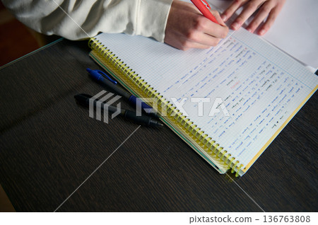 Teenage Boy Doing Homework In Cozy Home Study At Evening With Notebook And Pens Teenage Boy Doing Homework In Cozy Home Study At Evening With Notebook And Pens 136763808