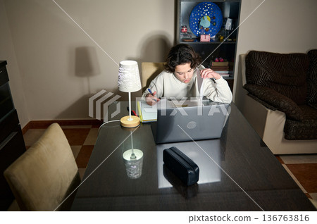 Teenage Boy Studying Homework At Laptop In Cozy Home Interior Evening Study Session 136763816