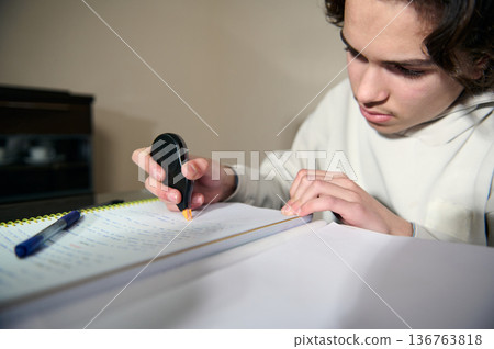 Teenage Boy Studying At Home Doing Homework With Correction Tape During Cozy Evening Study Session 136763818