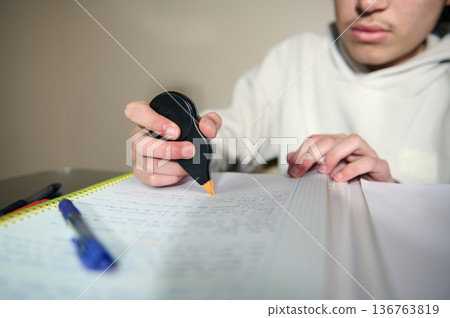 Teenage Boy Studying At Home Using Correction Tape While Doing Homework In Cozy Evening 136763819