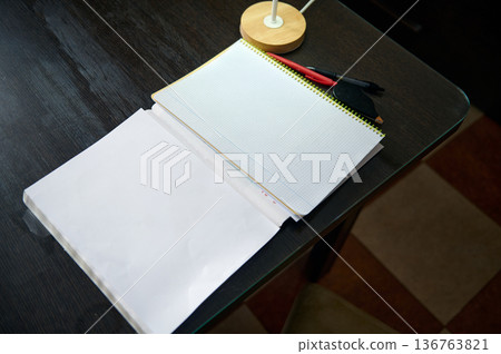 Teenage Boy Doing Homework At Desk In Cozy Evening Home Interior With Notebook And Pens 136763821
