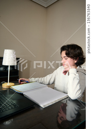 Teenage Boy Doing Homework In The Evening At Cozy Home Interior Teenage Boy Doing Homework In The Evening At Cozy Home Interior 136763840