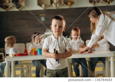 Front view of boy that is standing. Children in kindergarten with their teacher Front view of boy that is standing. Children in kindergarten with their teacher 136764083