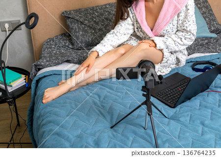 Adult woman sitting on a sofa and making a video for her subscribers 136764235