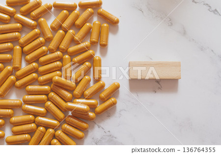 Natural curcumin capsules on marble and wood, showcasing clean eco-friendly wellness aesthetics with bright botanical supplements for modern biohacking and minimalist health visuals 136764355