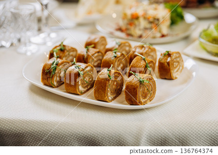 Savory stuffed pancake rolls served as festive appetizer on banquet table Savory stuffed pancake rolls served as festive appetizer on banquet table 136764374