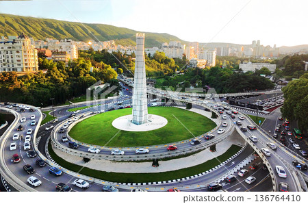 Aerial view on Tbilisi with Kura river and skyscrapers (maybe hotels) an and traffic on embankments . Greenery in May with fantastic plane trees Aerial view on Tbilisi with Kura river and skyscrapers (maybe hotels) an and traffic on embankments . Greenery in May with fantastic plane trees 136764410
