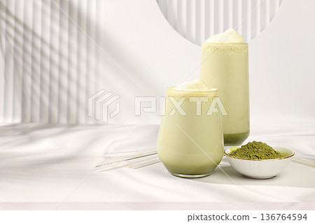 Green tea matcha latte with milk on elegant kitchen sunny background with palm leaves and matcha powder. Traditional Indian drink rich in antioxidants used for weight loss and treatment, 136764594