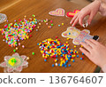 Children creating thermo mosaic figures with ironing beads fuse beads on wooden table 136764607