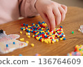 Children creating thermomosaic figures with ironing beads fuse beads on wooden table close-up 136764609