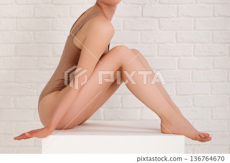 Beautiful slim body of young woman in beige bodysuit 136764670