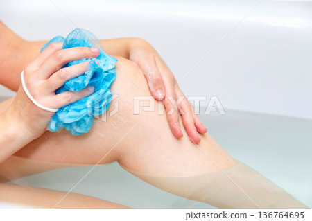 Woman washing her body in the bath. Close-up of female legs in a bathtub Woman washing her body in the bath. Close-up of female legs in a bathtub 136764695