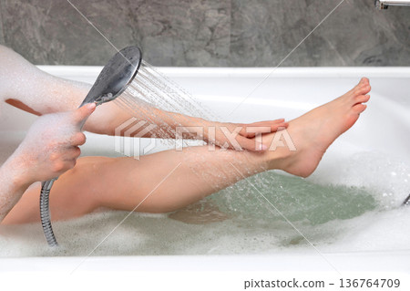 Woman taking a bath in bathroom. Closeup of female legs in foam. Woman taking a bath in bathroom. Closeup of female legs in foam. 136764709