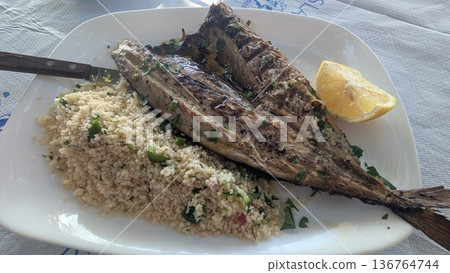 Grilled sun dried fish with couscous and a piece of cut lemon Grilled sun dried fish with couscous and a piece of cut lemon 136764744