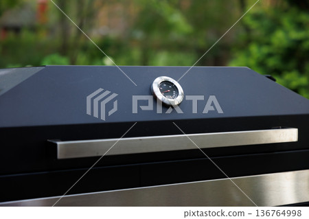 Perfectly smoked meat grilling under the sun in a lush garden setting during a summer afternoon 136764998