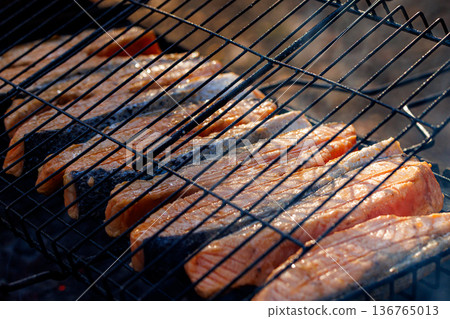 Grilling fresh salmon fillets over hot coals for a summer feast with friends and family 136765013