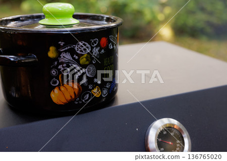 Cooking healthy meals in a colorful pot on a sunny day at a backyard kitchen Cooking healthy meals in a colorful pot on a sunny day at a backyard kitchen 136765020