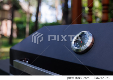 Grill thermometer reflecting the warmth of a summer garden gathering Grill thermometer reflecting the warmth of a summer garden gathering 136765030