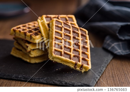 Sweet waffles with chocolate on wooden table. Sweet waffles with chocolate on wooden table. 136765083