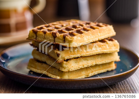 Sweet waffles with chocolate on plate on wooden table. 136765086