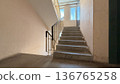 Concrete staircase inside residential apartment building, empty stairwell with metal handrails and natural daylight from windows. 136765258