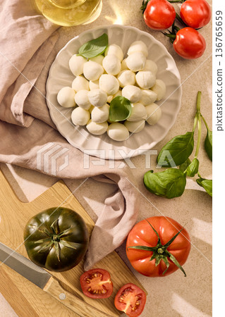 Mozzarella cheese with basil and cherry tomatoes on light background, top view Mozzarella cheese with basil and cherry tomatoes on light background, top view 136765659