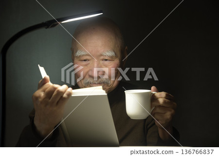 一位老人正在享受閱讀和咖啡。 一位老人正在享受閱讀和咖啡。 136766837