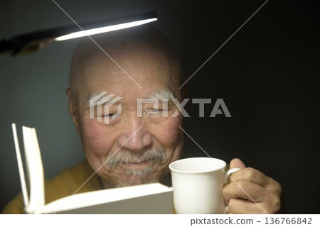 一位老人正在享受閱讀和咖啡。 一位老人正在享受閱讀和咖啡。 136766842