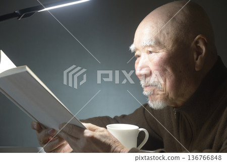 一位老人正在享受閱讀和咖啡。 一位老人正在享受閱讀和咖啡。 136766848