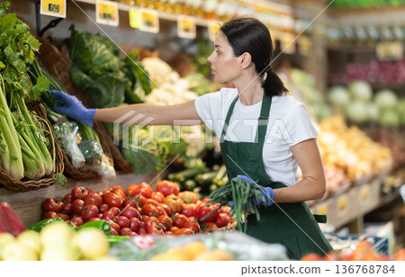 saleswoman lays out green onions on the counter saleswoman lays out green onions on the counter 136768784