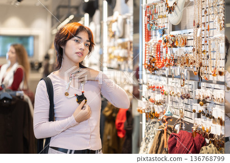Young woman chooses beads in accessories boutique Young woman chooses beads in accessories boutique 136768799