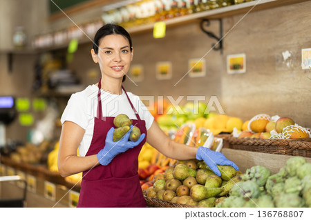 Female saleswoman holding pears in her hands 136768807