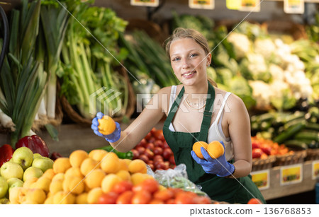 Young woman seller puts peaches in vegetable shop Young woman seller puts peaches in vegetable shop 136768853