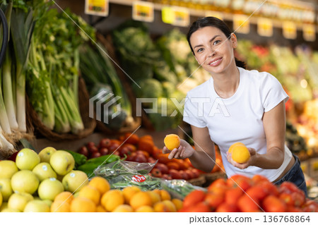 Woman near vegetable stand in store choose peach. Woman near vegetable stand in store choose peach. 136768864