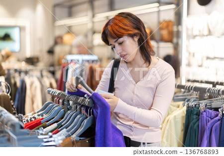 Young Asian woman choosing a wool sweater in a store Young Asian woman choosing a wool sweater in a store 136768893