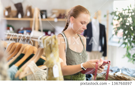 Young teen girl choosing a fashionable handbag in boutique 136768897