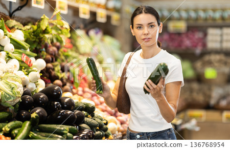 Young woman shopping in vegetable store and buy zucchini 136768954